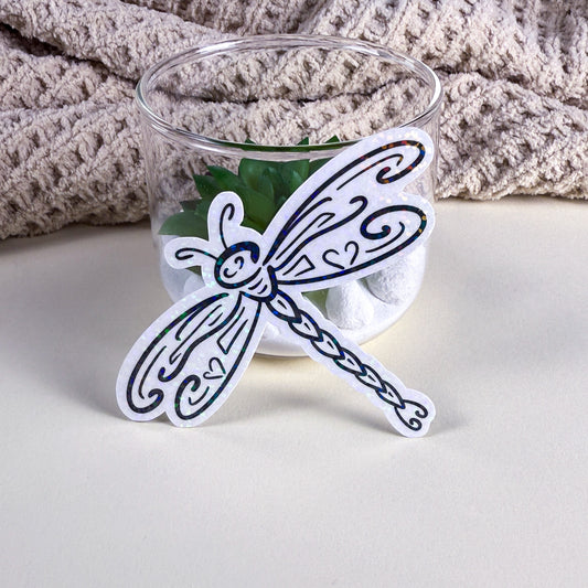 • Tribal dragonfly vinyl sticker in matte finish showing intricate black-and-white linework, Kittlins
• Holographic tribal dragonfly sticker catching light, applied to a dark water bottle
• Close-up of Kittlins Dragonfly sticker die-cut edge on a white background