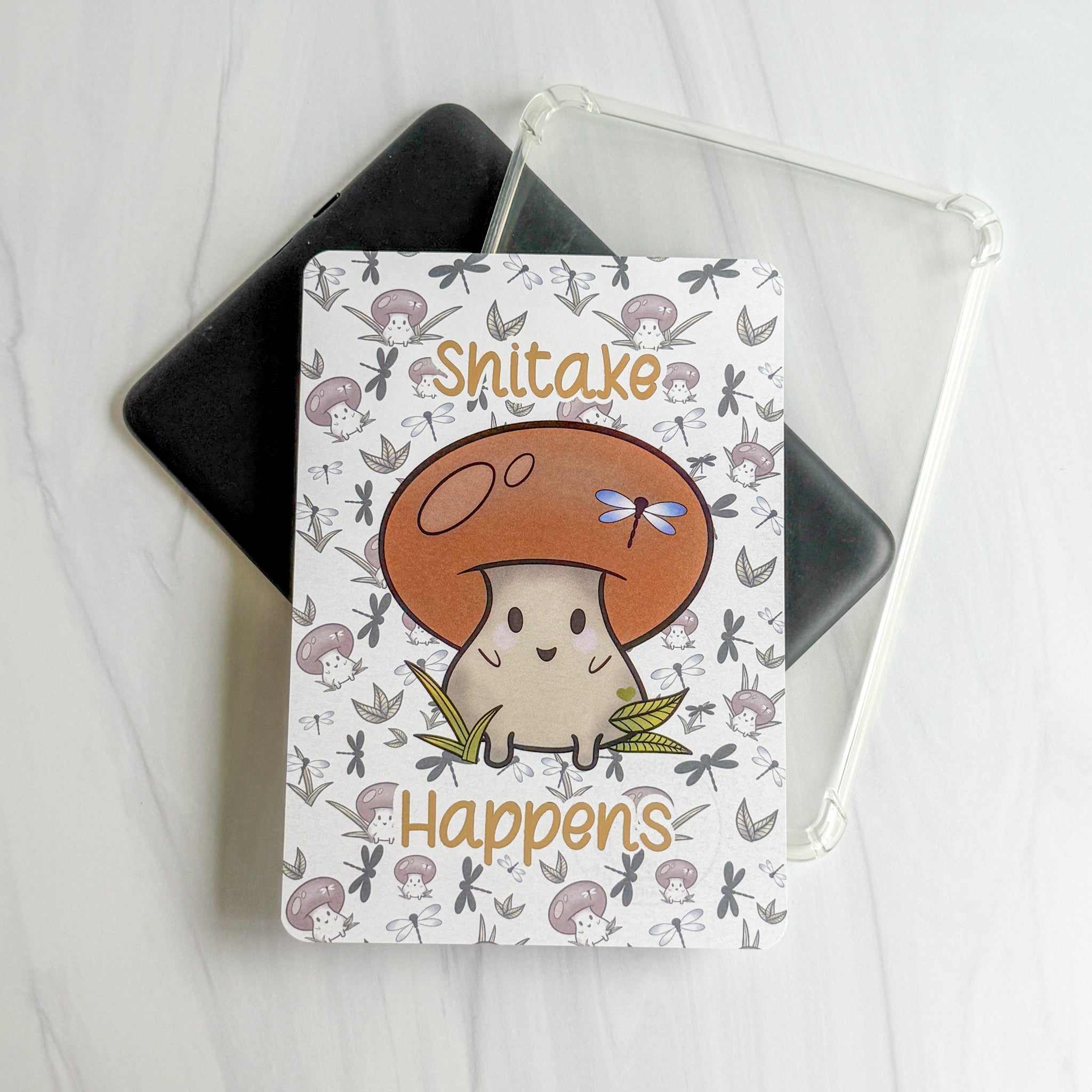 1.  Shitake Happens foiled Kindle insert with kawaii mushroom and dragonflies, Kittlins 2.  Kittlins mushroom pun Kindle insert shown under a clear case (device and case not included) 3.  Close-up of champagne-foiled Shitake Happens text on cardstock Kindle insert